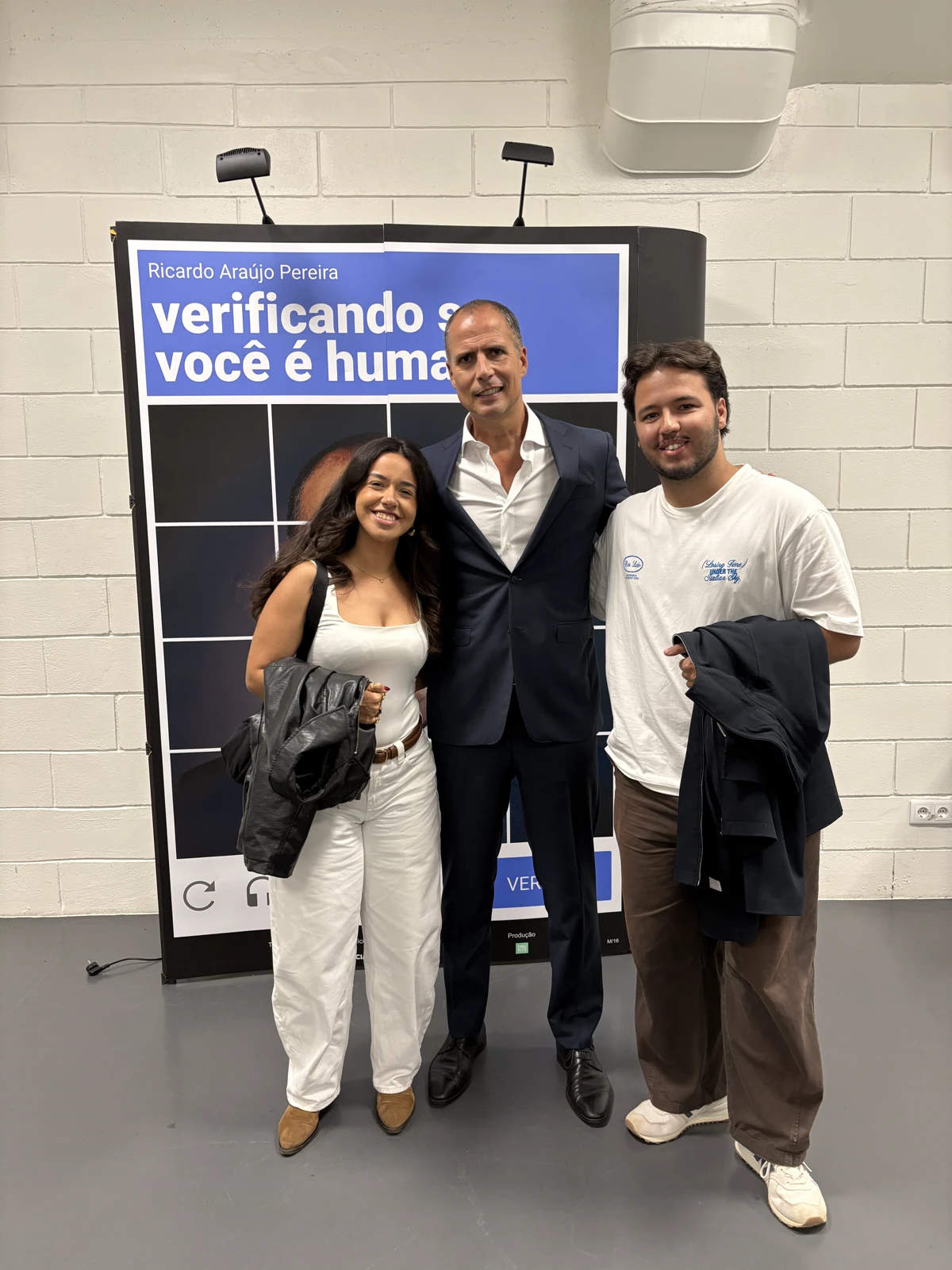 Fotografia de grupo junto a um cartaz de espetáculo