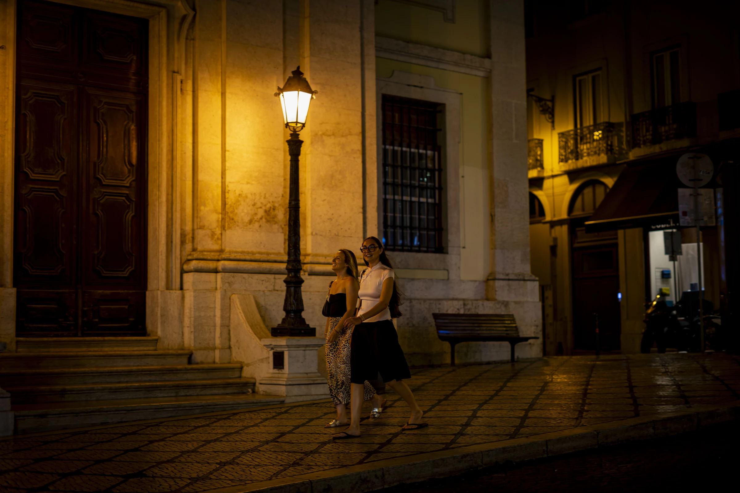 Duas pessoas caminham pela cidade à noite.