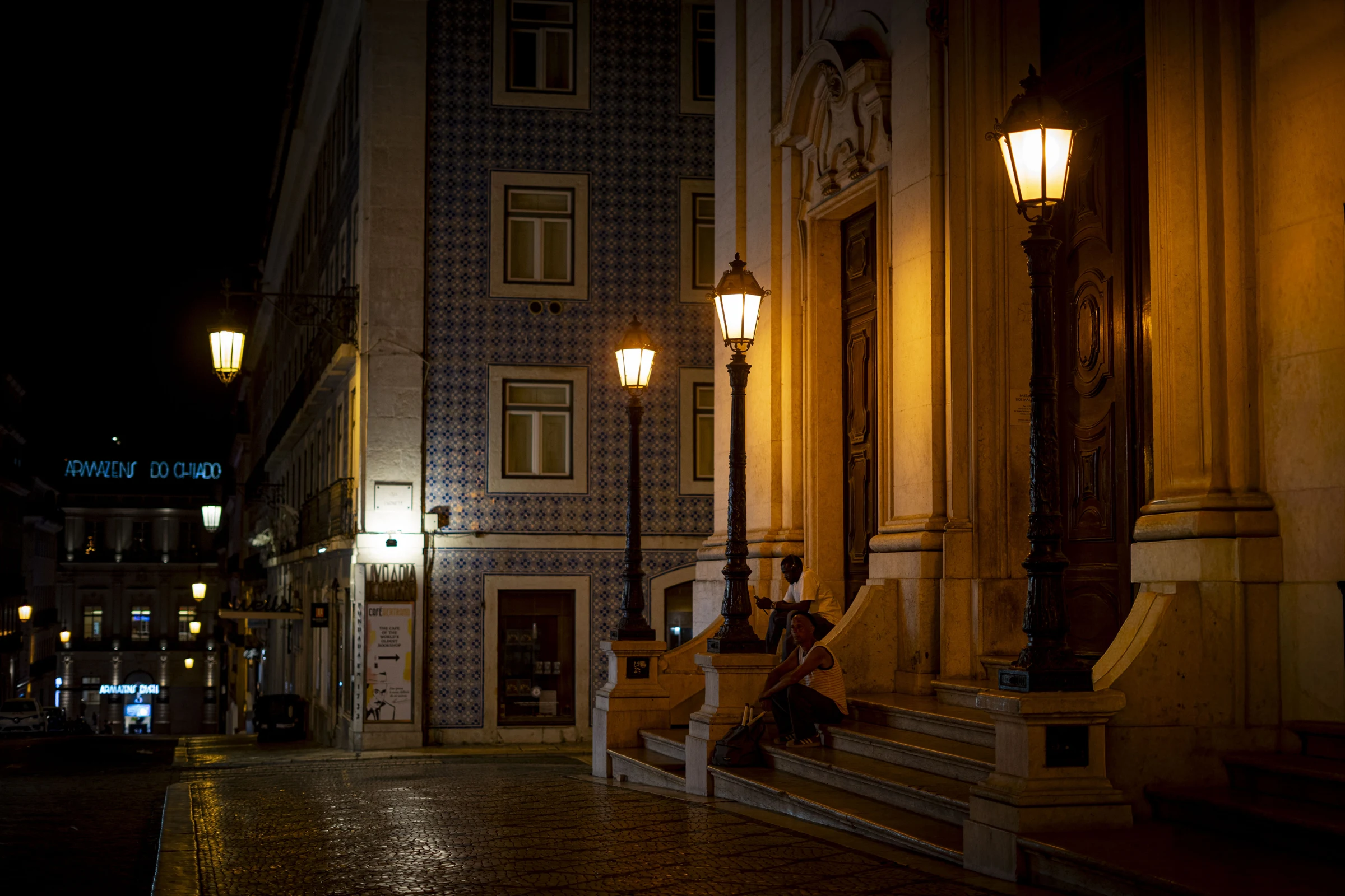 Pessoas junto a uma fachada iluminada.