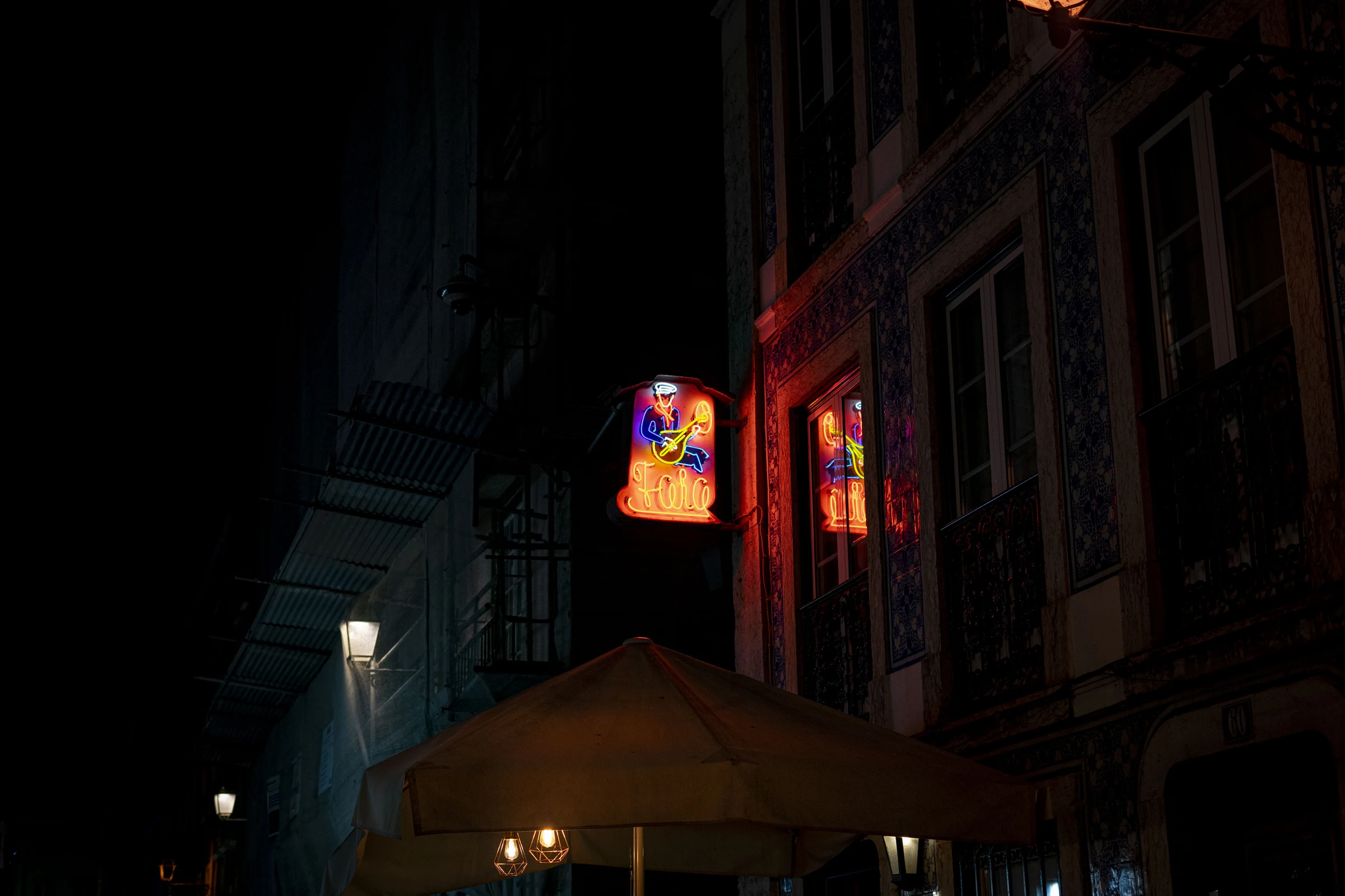 Um sinal luminoso de fado numa fachada escura.